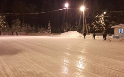 iltakuva luistelukentästä, muutama luistelija ja valot kentän yllä