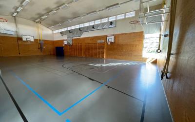 liikuntasalissa sininen mattolattia taustalla puolapuut ja koripallotelineet