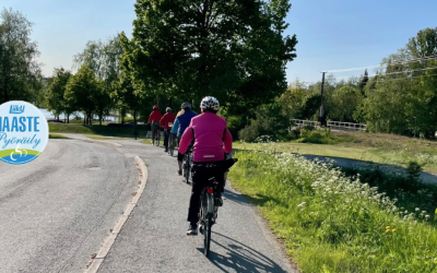 pyöräilijät polkevat asfaltti pyörätiellä taustalla puita ja rautatie