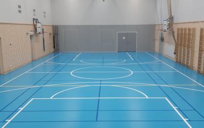 Sisäliikuntasalissa sininen lattia ja reunalla puolapuut