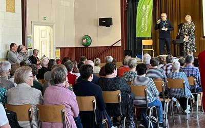 ihmisiä istuu salissa kuuntelemassa kahta ihmistä lavalla