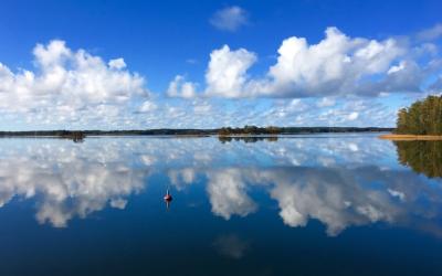 Merimaisema, pilvet heijastuvat tyynestä veden pinnasta.
