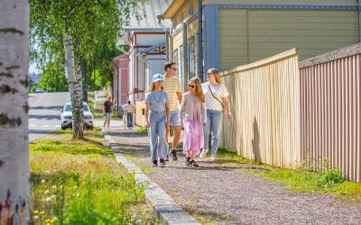 Lapsiperhe kävelee puutalokeskustassa.