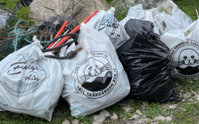 Kuvassa täyteen kerättyjä roskapusseja luonnossa. Roskapusseissa lukee "Pidä saaristo siistinä"