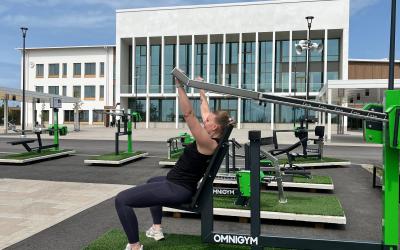 nainen ulkokuntosalilaitteissa taustalla rakennus