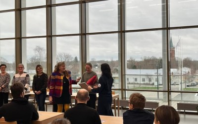 vammaisneuvoston juhlassa kunniakirjan jako taustalla kaupunki ikkunan takaa