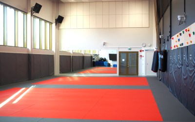 budosali jossa taustalla peilit sivuilla kiipeilyseinä ja nyrkkeilysäkit