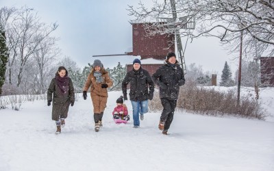 neljä aikuista ja lapsi talvimaisemissa tautalla tuulimylly