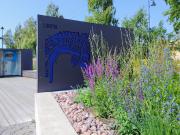 Kalarannan laituri, ulkoilmanäyttelyn Lontoota koskevat esittelytaulut ja kukkia.