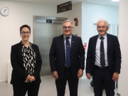 Nainen ja kaksi miestä seisoo ja katsoo hymyillen kameraan.