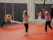 Lapset temppuilevat budosalissa köysien ja renkaiden kanssa