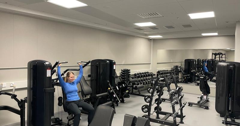 panoraamanäkymä kuntosalilta, nainen treenaa pystypunnerusta