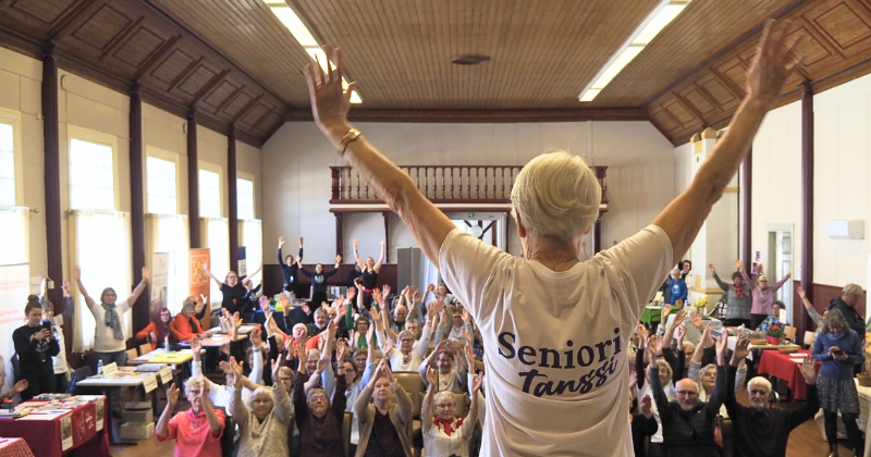 Seniorimessujen tuolitanssi, etualalla esitanssija ja taustalla yleisöä.