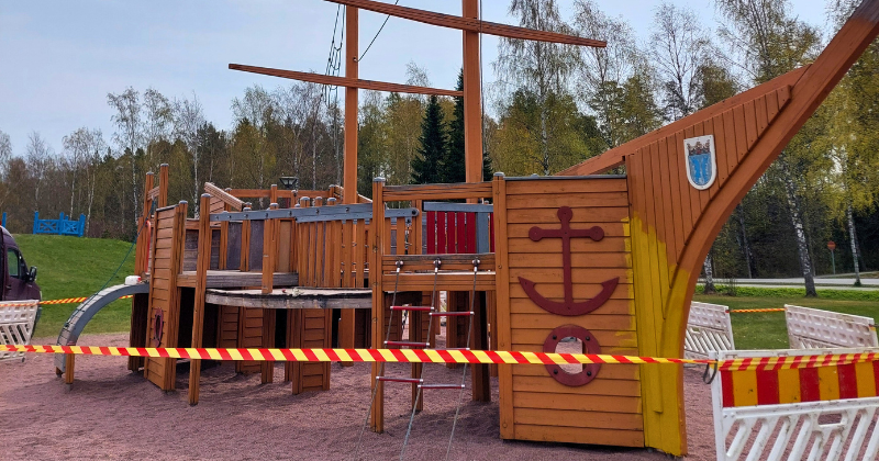 Puinen iso lasten kiipeilyleikkilaiva, jonka ympärille vedetty huomionauha laivan maalaustöitä varten.