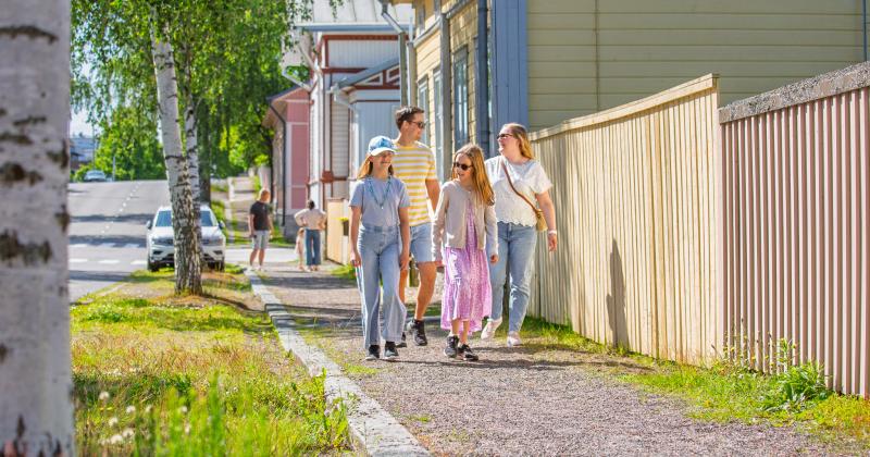 Lapsiperhe kävelee puutalokeskustassa.