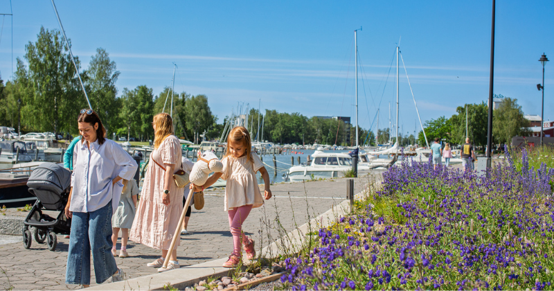 Naisia ja lapsia kävelemässä Uudenkaupungin kaupunginlahden rannalla kesäpäivänä.