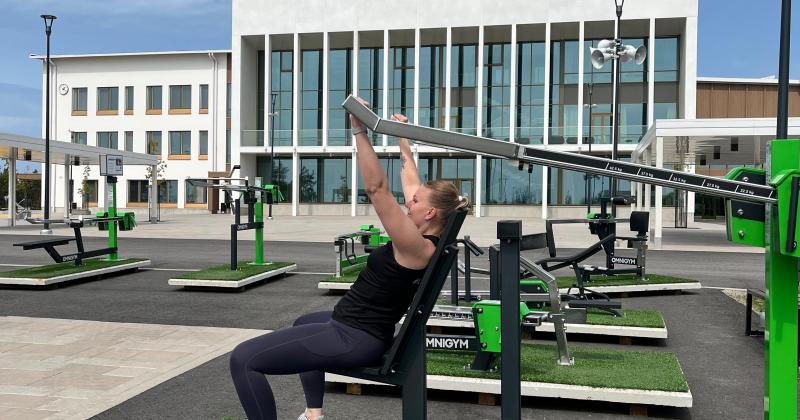 nainen ulkokuntosalilaitteissa taustalla rakennus