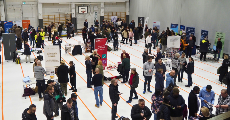 Iso määrä ihmisiä yläviistosta kuvattuna sisäliikuntahallissa juttelemassa.